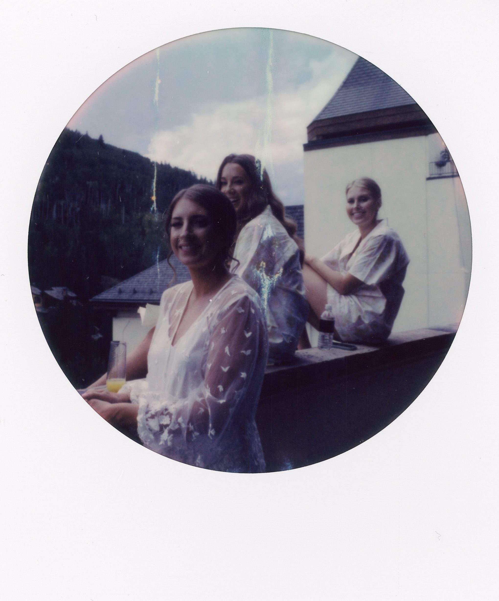Three girls sit on a rooftop in Vail. Bridal polaroid portraits taken in Colorado by Stephanie Mikuls Photography, a wedding photographer based in Colorado.